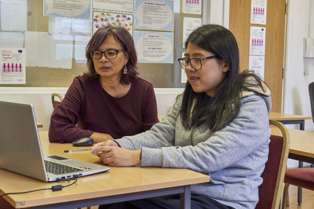 2 woman working at a computer together